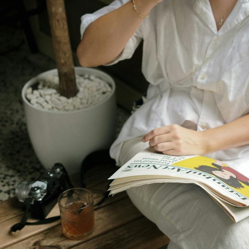 woman sitting drinking a glass of water and reading a paper